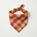 Spiced orange plaid flannel dog bandana tied in a triangle knot on a plain background